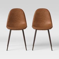 two brown chairs sitting next to each other on top of a white floor with black legs