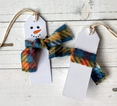 two snowmen with scarfs hanging from twine on white wooden planked surface