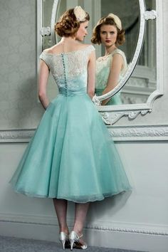 a woman standing in front of a mirror wearing a dress with lace on the top