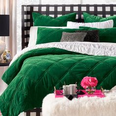 a bed with green comforter and white pillows