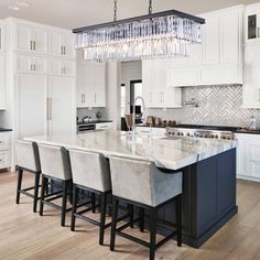 a large kitchen with white cabinets and marble counter tops, along with an island in the middle