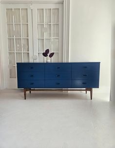 a blue dresser sitting in the middle of a living room next to a white wall