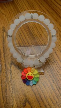 a plastic ring with a rainbow colored smiley face on it and beads around the rim