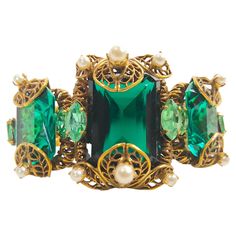 Possibly as old as the 1800s or a later Baroque-revival imperceptible reproduction, this antique handcrafted gilt silver filigree-frame textured-chain link bracelet likely originated in the European region of Austria-Hungary-Germany. We partly base this on its brilliant blue-green glass jewels in the rare trace-mineral saturated color of authentic alkaline Columbian emeralds. Including a decorative box-clasp, the ornate bracelet also features 14 prong-set round white pearls mostly mounted on the open-work filigree and 6 marquise-cut vanadium chrysoberyl mounted on both sides of the three linked frames. Along with the shifting shadows of the partly reflective filigree, the refracted light cast sideways by the paler lime-green beryl through the emerald-cut and scissor-cut vivid-glass jewels Antique Jeweled Jewelry For Formal Occasions, Antique Formal Jewelry, Antique Green Jewelry For Evening, Ornate Jeweled Bracelets For Formal Occasions, Vintage Gemstone Jewelry For Evening, Victorian Jeweled Evening Jewelry, Vintage Jeweled Jewelry For Evening, Victorian Green Jewelry For Party, Ornate Green Jewelry For Evening