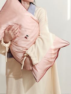 a woman holding a pink pillow in her arms