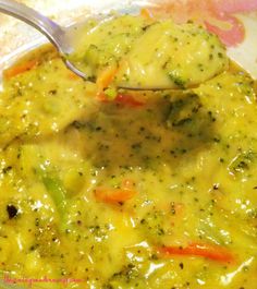 a spoon with broccoli and carrots in it is being held over a casserole dish