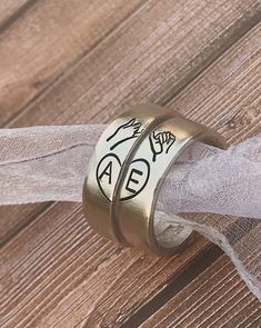 two wedding rings with names on them are tied to a piece of fabric that is attached to a wooden fence