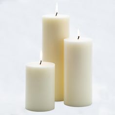 three white candles sitting next to each other in front of a white background with no one around them