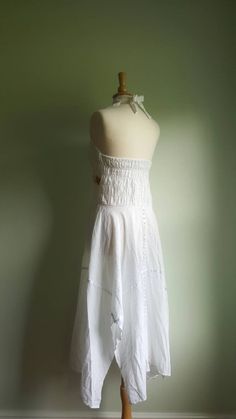 Embroidered sunflowers pop on this gorgeous white cotton-gauze dress. The lacy bodice flares into an ultra-full, handkerchief-hem skirt, with white satin ribbon accents. Easy fit, with a ruched, elasticized back and halter tie at neck. Best fits medium/large sizes. Era: 1970s Label: none ➸ visit on instagram | provenance_vintage White Cotton Maxi Dress With Lace Trim, White Cotton Halter Neck Maxi Dress, Vintage White Sleeveless Sundress, White Sleeveless Vintage Sundress, Bohemian Halter Neck Dress With Lace Trim, White Fitted Halter Neck Sundress, White Halter Neck Sundress, Fitted Cotton Sundress For Festivals, Bohemian Cotton Halter Neck Maxi Dress