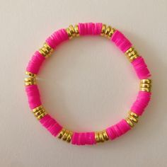 a pink and gold beaded bracelet on a white surface