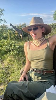 a woman sitting on the back of a truck with a giraffe in the background