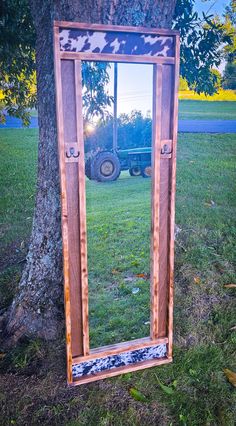 a mirror sitting on the ground next to a tree in front of a tractor tire