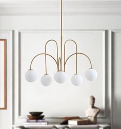 a white and gold chandelier hanging from a ceiling in a room with a table