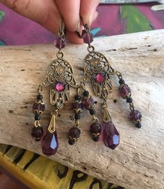 Bohemian Hamsa Earrings Purple Czech Glass Dangle Earrings Amethyst Glass Brass Earrings Festival Spiritual Hand Miriam Belly Dancer I created these fabulous earrings from vintage components of a bronze toned filigree Hamsa and beautiful purple amethyst glass faceted beads and tear drops. Hung from bronze toned lever back ear wires, these lightweight earrings measure 3" in length and 15/16" in width. Super fun, they swish and sway! Please see all photographs as they are considered to be part of the description.  All vintage items are sold "as is".  Please message me with any questions prior to purchase.  All items shipped in recycled Planet Friendly Packaging 🌎 Spiritual Hand, Antique Turquoise Jewelry, Hamsa Earrings, Lavender Earrings, Vintage Jewelry Repurposed, Festival Earrings, Tear Drops, Belly Dancer, Assemblage Jewelry