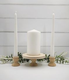 three white candles sitting on top of each other