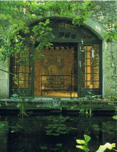 an old building with water and plants surrounding it