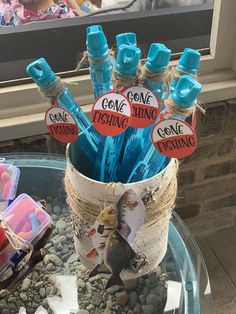 a glass table topped with lots of blue pens and paper stick holders on top of rocks