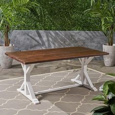 a wooden table sitting on top of a tiled floor next to potted planters