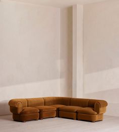 a brown couch sitting on top of a white floor next to a tall column in a room