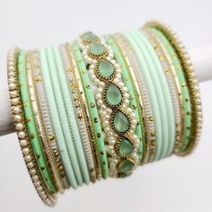 Indulge in the refreshing beauty of our Mint Green, Pearl, and Gold bangle set, designed to adorn one arm with grace and elegance. This exquisite ensemble features a collection of bangles in varying shades of mint green, offering a serene and tranquil aesthetic. The addition of lustrous pearls adds a touch of sophistication and classic charm, while the gold accents provide a radiant and opulent allure. Whether worn individually or stacked together, this bangle set adds a touch of refined glamour Shades Of Mint Green, Tranquil Aesthetic, Silk Bangles, Gold Bangle Set, Gold Bangle, Bangle Set, Gold Bangles, Gold Accents, Mint Green