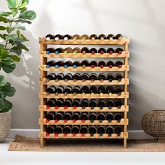 a wooden wine rack filled with lots of bottles next to a potted green plant