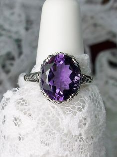 "Natural Purple Amethyst Ring Description Edward Design#70 (smaller version) MADE TO ORDER Inspired by Edwardian jewelry of the early 1900s, I now offer this lovely Antique reproduction ring in sterling silver. This gorgeous ring is set with a stunning 3.32ct Natural purple amethyst gemstone. This genuine amethyst has excellent color and clarity. The oval cut amethyst is 12mm (1/2th of an inch) Long by 10mm Wide (3/8th\"). The ring sits 6mm off the finger. The inside of the band s marked 925 for Oval Purple Diamond Cut Jewelry, Purple Oval Diamond Cut Jewelry, Vintage Oval Gemstones For Wedding, Oval Vintage Gemstones For Wedding, Classic Wedding Gemstones With Diamond Cut, Purple Anniversary Rings With Intricate Design, Oval Hallmarked Amethyst Ring In White Gold, Classic Oval Amethyst Ring With Accent Stones, Oval Gemstone Filigree Ring For Formal Events