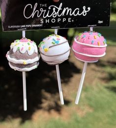 three decorated donuts are on sticks in front of a sign that says the christmas shoppe