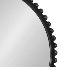 a round mirror with black beading around the edges