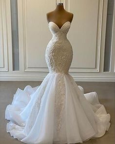 a wedding dress on display in front of a white wall with a mannequin