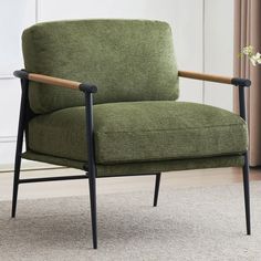 a green chair sitting on top of a carpeted floor next to a vase with flowers