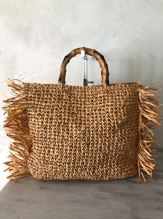 Bohemian Natural Shoulder Bag For Shopping, Brown Bags With Bamboo Handle For Beach Season, Bohemian Crochet Bag With Tassels For Beach Season, Summer Fringe Bags For Daily Use, Beach Season Shopping Bag With Bamboo Handle, Chic Straw Beach Bag With Tassels, Beach Bag With Bamboo Handle And Jute Material, Bohemian Straw Bag With Bamboo Handle For Shopping, Chic Beach Straw Bag With Tassels