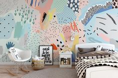 a bedroom with colorful wallpaper and a white rocking chair in front of the bed