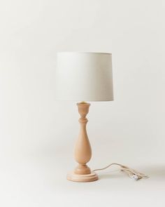 a small wooden table lamp with a white shade on the base and a cord attached to it