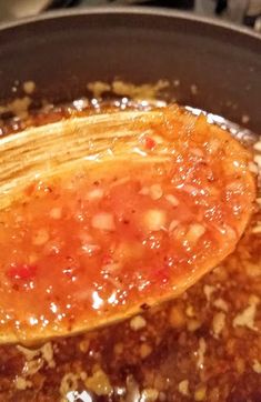 a wooden spoon in a pot filled with chili and cheese sauce on top of a stove