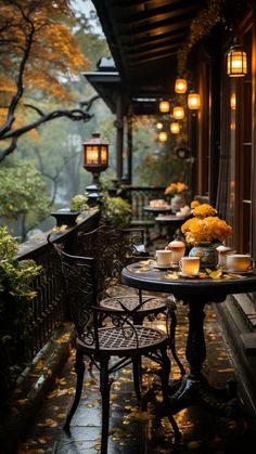 an outdoor table and chairs with candles on it in front of a porch filled with fall leaves