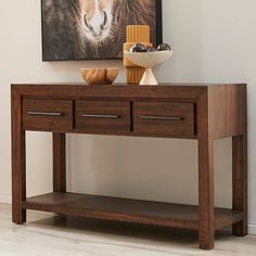 a wooden table with two drawers and a painting on the wall