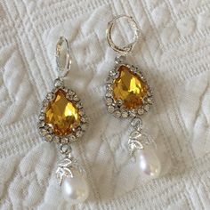 "Handmade Yellow Teardrop Shaped Stone Surrounded by Clear Rhinestones With an Oval Real Pearl Set in a Leaf Design. Stunning Eye Catching Yellow Stone in Feminine Style Setting. Great for modern wear or costuming. 925 Silver Plated Loop Lever Back Pierced Earrings. Pair of reproduction historic earrings, New. Period appropriate for 18th and 19th Century dressing. Good for modern wear, also. Size: 9/16\" X 3/4\" Large Stone Setting, 1 1/2\" Dangling Length, 1 1/2 cm X 4 cm. For other vintage jew Silver Teardrop Clip-on Earrings, Elegant Yellow Dangle Clip-on Earrings, Silver Teardrop Clip-on Crystal Earrings, Silver Teardrop Crystal Clip-on Earrings, Jeweled Dangle Earrings For Anniversary, Pear-shaped Crystal Earrings As A Gift, Teardrop Crystal Earrings With Sparkling Stones For Anniversary, Pear-shaped Crystal Earrings Gift, Sparkling Stone Pear Earrings As Gift