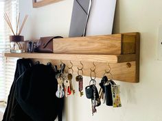 a wooden shelf with key hooks and keys hanging from it's sides, in front of a window