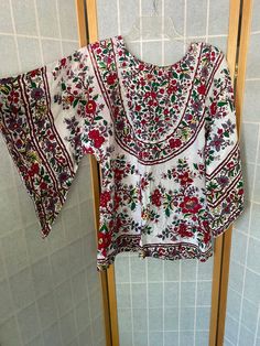 "1970's handmade shirt with colorful floral pattern and asymmetrical bat sleeve. Several spots of color bleeding within the fabric Bust: 40\" Shoulder to hem: 29\""