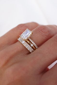 a woman's hand with two wedding rings on top of her finger and the ring is made out of gold