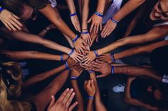 a group of people standing in a circle with their hands on top of each other