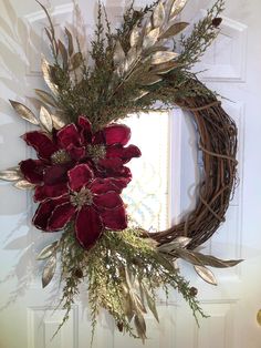 a wreath with red flowers is hanging on the front door