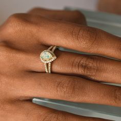 a woman's hand wearing a ring with an opalite in the center