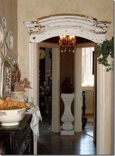 an entry way with a bowl of food on the table and vases filled with flowers