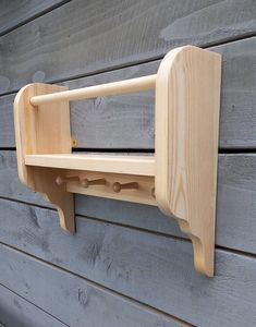 a wooden shelf mounted to the side of a building with hooks on it's sides