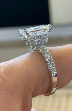 a woman's hand holding an engagement ring with a large diamond in the center