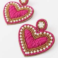 two pink and white beaded heart shaped earrings on a white surface, with pearls in the center