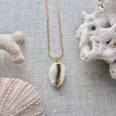 We love this fun and summery, beachy necklace. Answer the siren's song and get one for yourself or someone you love. Would make a great gift for the surfer or beach-lover in your life! A 14k gold electroplated cowrie shell dangles from a lustrous, high quality gold filled snake chain. The perfect summertime accessory! Chain length 16"✦ JEWELRY CARE ✦✧ Warm water and a soft cloth are the best thing you can do to maintain the beauty of your jewelry.✧ Jewelry polishing cloths work great and are non Gold Shell Necklace With Starfish Charm For Summer, Beachy Gold Shell Necklace As A Gift, Beachy Gold Shell Necklace For Gifts, Beachy Gold Shell Necklace For Gift, Beachy Gold Shell Necklace Perfect For Gifts, Starfish Charm Strand Jewelry For Vacation, Starfish Charm Jewelry For Vacation, Gold Shell Necklace With Starfish Charm For Vacation, Strand Jewelry With Starfish Charm For Vacation