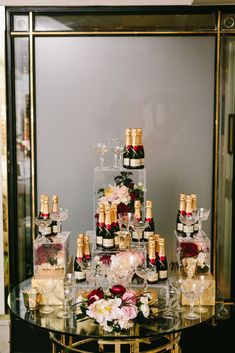 a table topped with lots of bottles of wine and vases filled with flowers next to each other