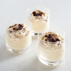 three glasses filled with dessert sitting on top of a table